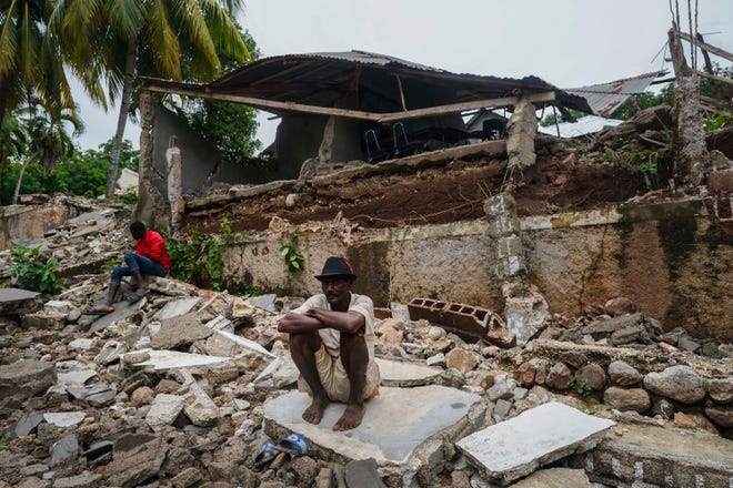 A man crouches on the rubble of the hospital destroyed by the earthquake in Fleurant, Haiti, Tuesday, Aug. 17, 2021, three days after the 7.2-magnitude quake hit the Caribbean nation.