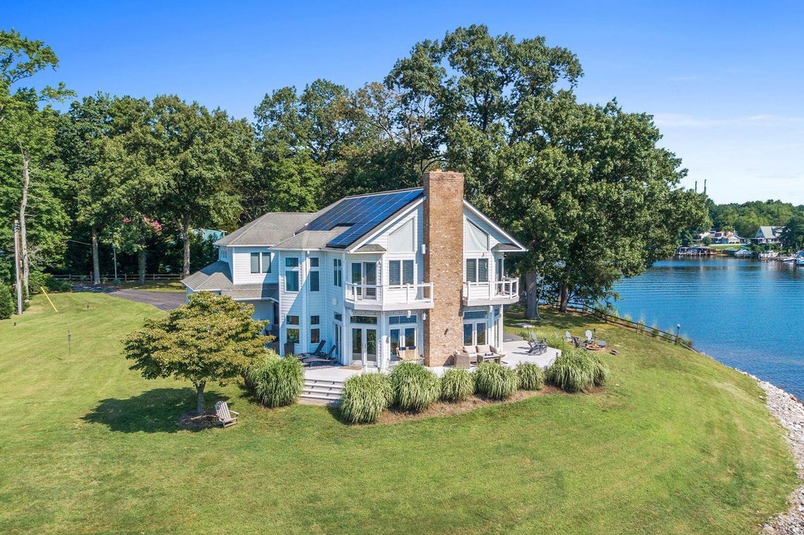 Two story home painted blue with large yard near water