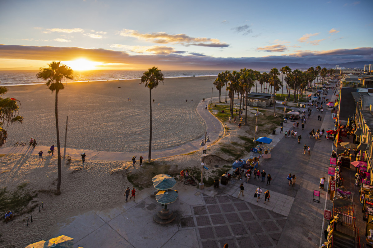 Tourists walking on footpath by beach during sunset _ getty